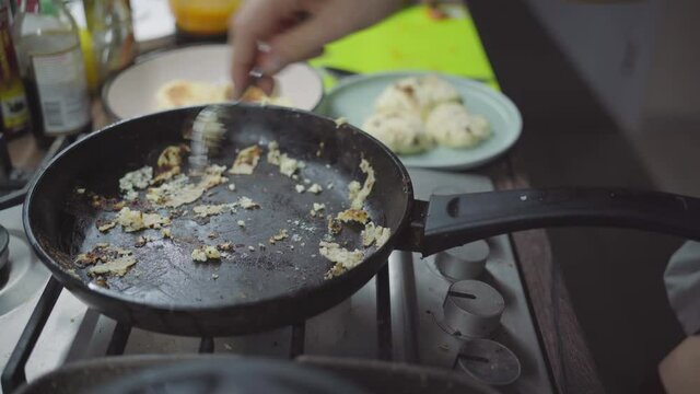 the cook's in the kitchen, pancakes are burnt, he is ripping a pancake from a frying pan