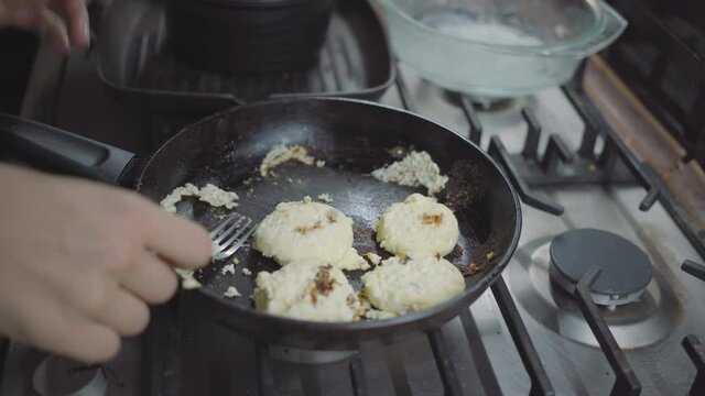 a woman in the kitchen, her pancakes are burnt, she rips a pancake from a frying pan