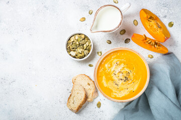 Pumpkin soup puree in the craft bowl. Top view image at white table.