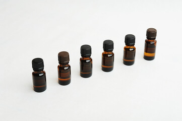Row of small bottles of dark glass on a white background, copy space. Essential oils, cosmetic concept