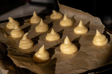 Choux dough for profiteroles on baking paper, beautiful sunshine.