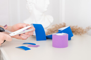 Woman holding scissors, cutting kinesio tape. Anti-aging treatment against wrinkles. Aesthetic...