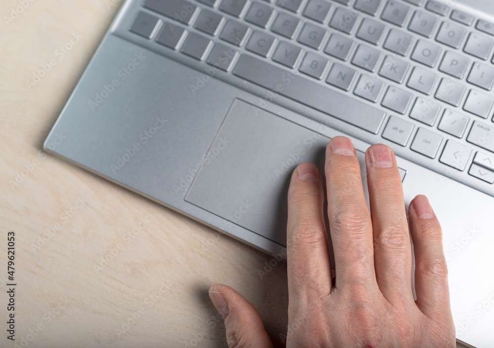 Poster hand on laptop touchpad, tapping and scrolling with fingers closeup.