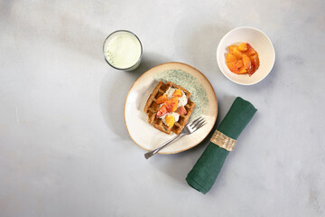 Vegan, gluten free waffles with pudding, oranges and green milk on neutral background. Healthy meal, tasty homemade breakfast.