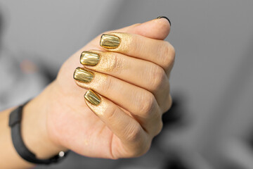 Bright festive, New Year's, brilliant manicure on female hands. Nail design in gold. The process of...