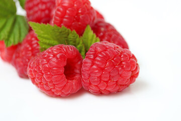 Red raspberry with green leaves on white background. Ripe juicy berries close up, summer crop