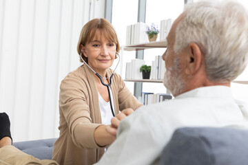 Fototapeta premium senior woman doctor on home visit and examining elderly man patient by stethoscope
