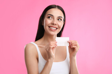 Beautiful woman with mattifying wipe on pink background