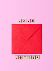 Top view of red envelope on pink and wooden words love letter. St Valentine, message, proposal, romance concept. 
