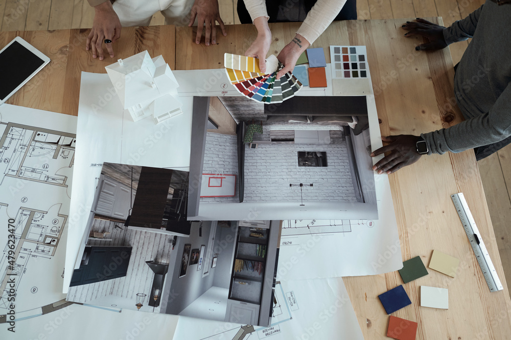 Poster hands of female designer with color swatches and her two male colleagues standing by table and worki