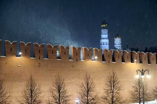 The Kremlin Wall and cathedrals after it in Moscow Russia with holiday lighting during cold Russian winter blizzard on night