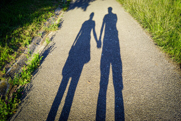 Stretched shadow of a couple holding hands on asphalt