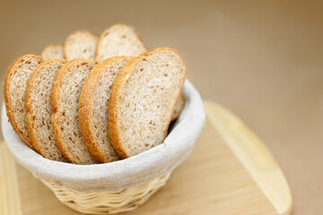 Fresh cereal bread in a wicker basket. The bread is sliced. Beige background, wooden board, linen cloth in a basket. Free space for text. Healthy organic food concept.
