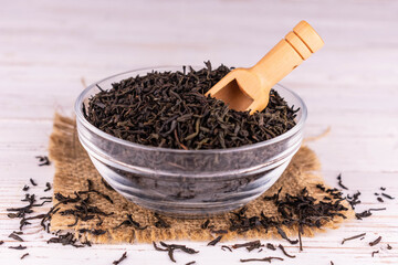 Black tea in a glass bowl on a white background.
Close-up.