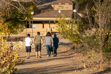 Fototapeta na wymiar A Family Enjoying a Beautiful Day in a Recreational Lake Park Taking a Walk
