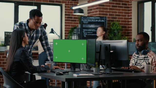 Two software developers analyzing source code looking at green screen chroma key mockup with coworker sitting at desk writing algorithm. Software developers working on artificial intelligence project.