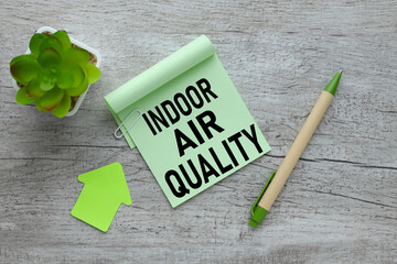 INDOOR AIR QUALITY. Green notes in the workplace with stationery on a wooden table.