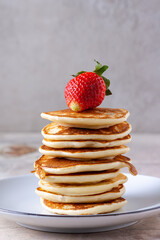 drops of honey flow down from strawberries onto a stack of pancakes