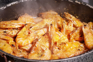 Prawns cooking. Frying pan with fried shrimp with garlic rosemary and spices with smoke, close up. Mediterranean, keto diet