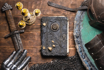 Ancient book and medieval weapon on the table flat lay background. Knight story book concept.