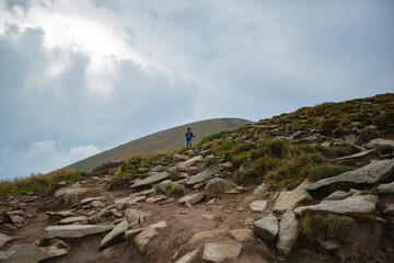 People descend down a large green mountain range. Mountain Hiking