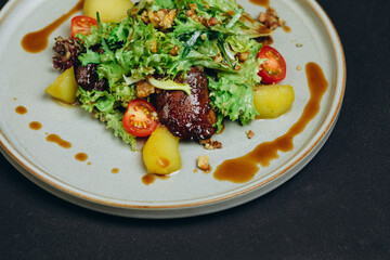 The salad with some meat and potatoes is served to the visitors of the restaurant.