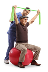 Physical therapist working with an elderly man sitting on an exercise ball and using a stretching...