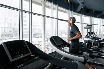 Fototapeta na wymiar Self-determined senior man exercising on treadmill