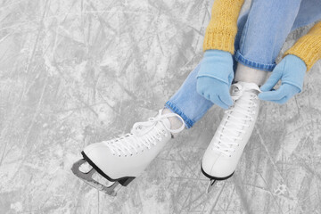 Woman lacing figure skates on ice, top view. Space for text