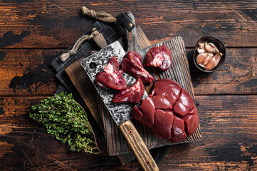 Raw lamb kidney, fresh offal meat on butcher board with herbs. Wooden background. Top view