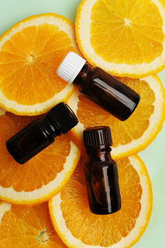 Citrus orange essential oil in dark glass bottles on fresh slices of orange. Cosmetic, healthy concept