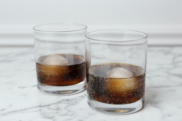 Cocktails with ice balls on white marble table