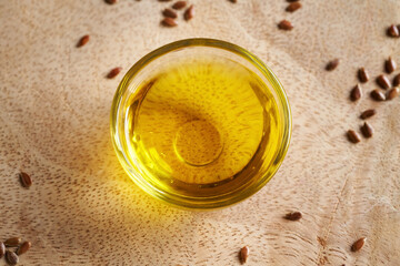 A bowl of flax seed oil with linseeds on a table