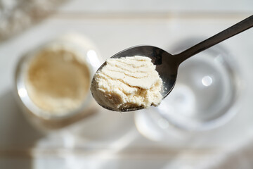 Preparation of a protein drink - whey protein powder on a spoon, top view - obrazy, fototapety, plakaty