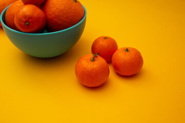 Citrus oranges in a bowl on a yellow background