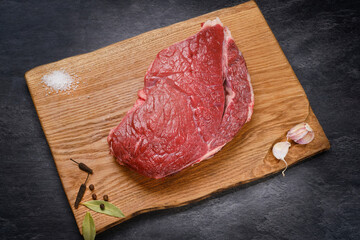 Raw beef meat. Fresh cut of beef on wooden kitchen board with spices. Raw steak on cutting board ready to cook. Selective focus