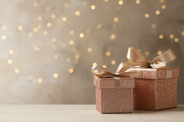 Beautiful gift boxes on light table against blurred festive lights, space for text