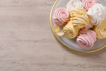 Plate with delicious marshmallows on wooden table, top view. Space for text