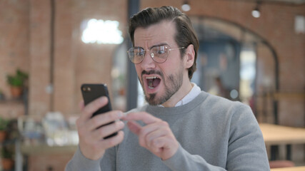 Young Man having Loss while Using Smartphone