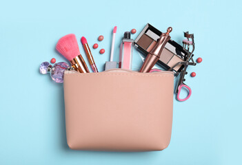 Cosmetic bag and makeup products with accessories on light blue background, flat lay