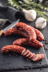 Smoked sausages with pepper, rosemary and garlic on black table.