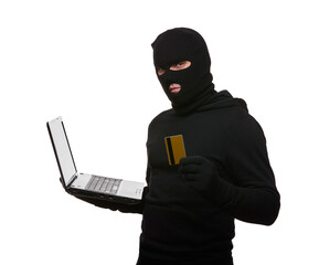 Thief in balaclava with laptop and credit card on a white background.