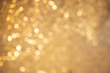 Fototapeta premium Blurred defocused golden glitter background. Yellow shimmer bokeh . Festive golden soft focus background.
