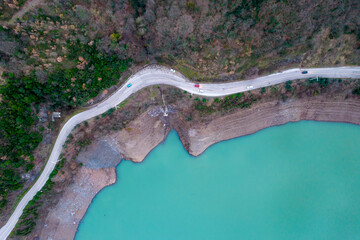Long road between lake and forest. Aerial top view.