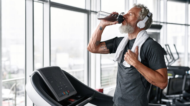 Mature man drinking water from bottle, the towel on shoulder
