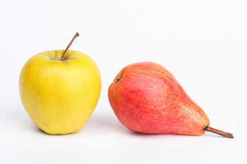 Yellow apple and a red pear on a white table