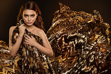 Fashion Woman with Golden Wild Animal Print Dress and flying Fabric. Beauty Brunette Model Portrait...