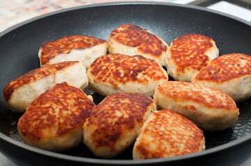 meat cutlets fried in a pan with green onions