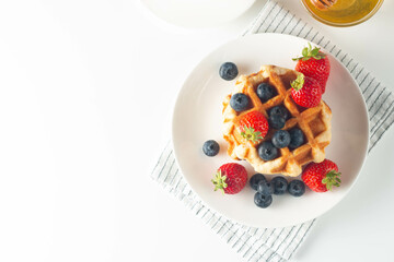 Fresh homemade food of berry Belgian waffles with honey, chocolate, strawberry, blueberry, maple syrup and cream. Healthy dessert breakfast concept with juice