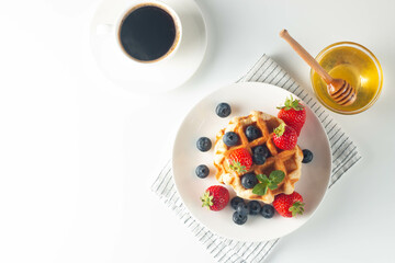 Fresh homemade food of berry Belgian waffles with honey, chocolate, strawberry, blueberry, maple syrup and cream. Healthy dessert breakfast concept with juice